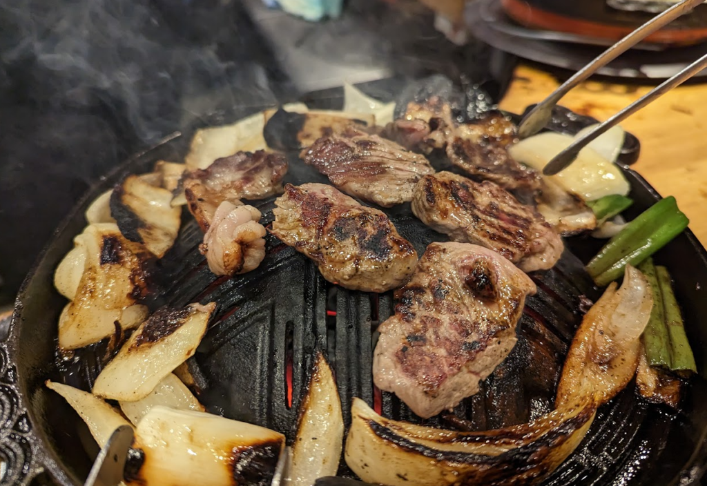 sheep meat with vegetables on a dome-shaped grill